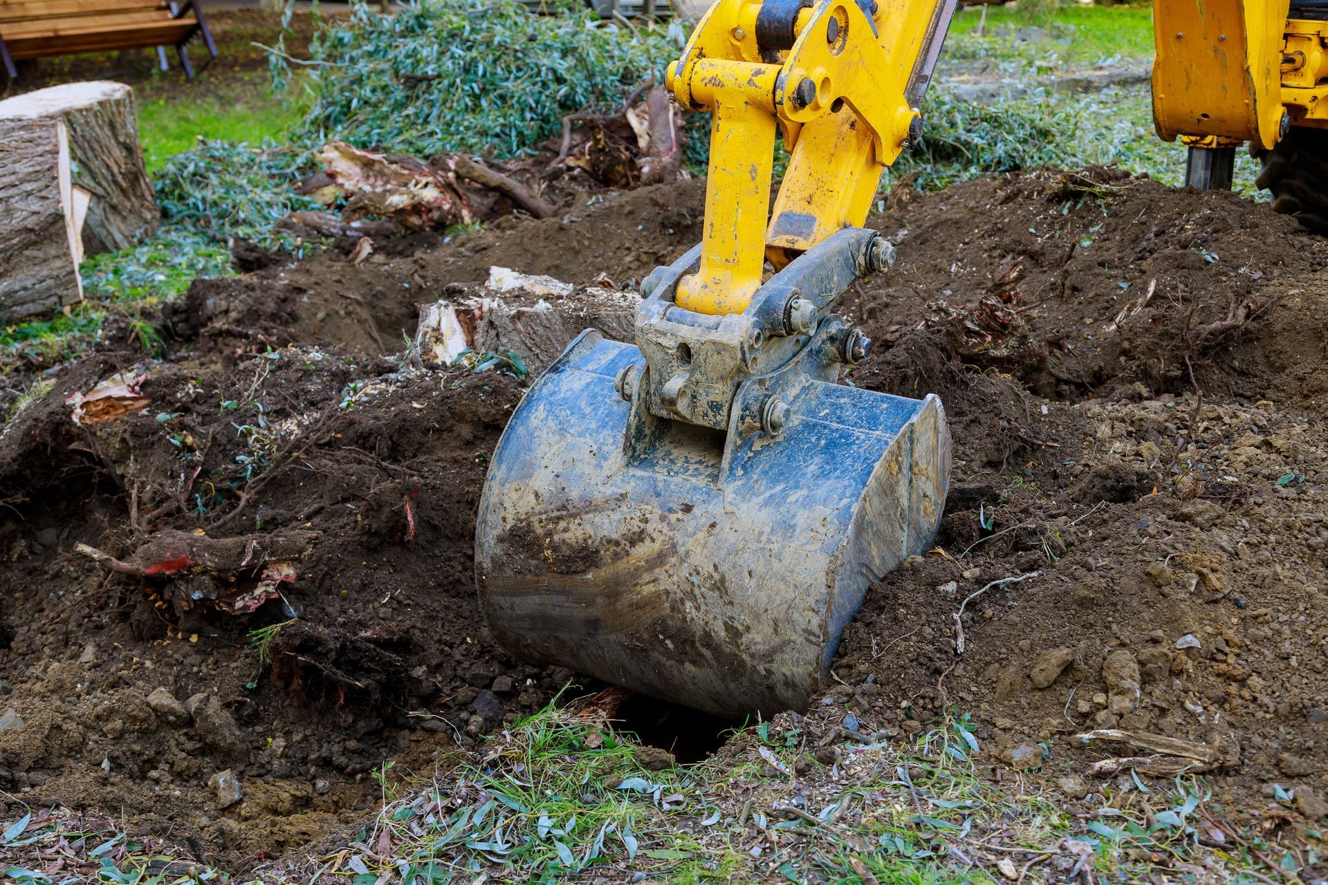 Excavator digging soil and removing tree roots during land clearing work. Excavator digging soil and removing tree roots during land clearing work.