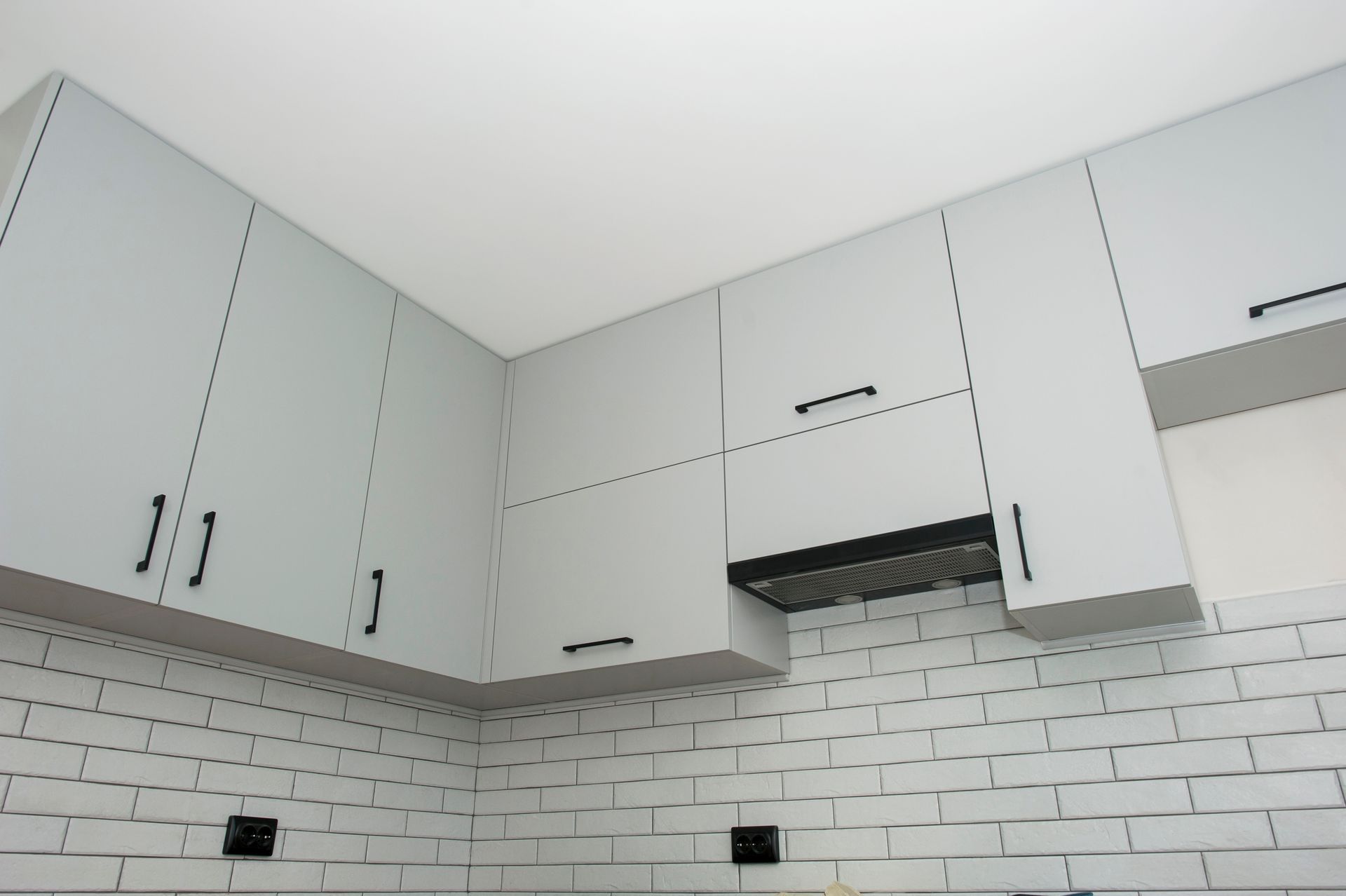 A kitchen with white cabinets and a white brick wall