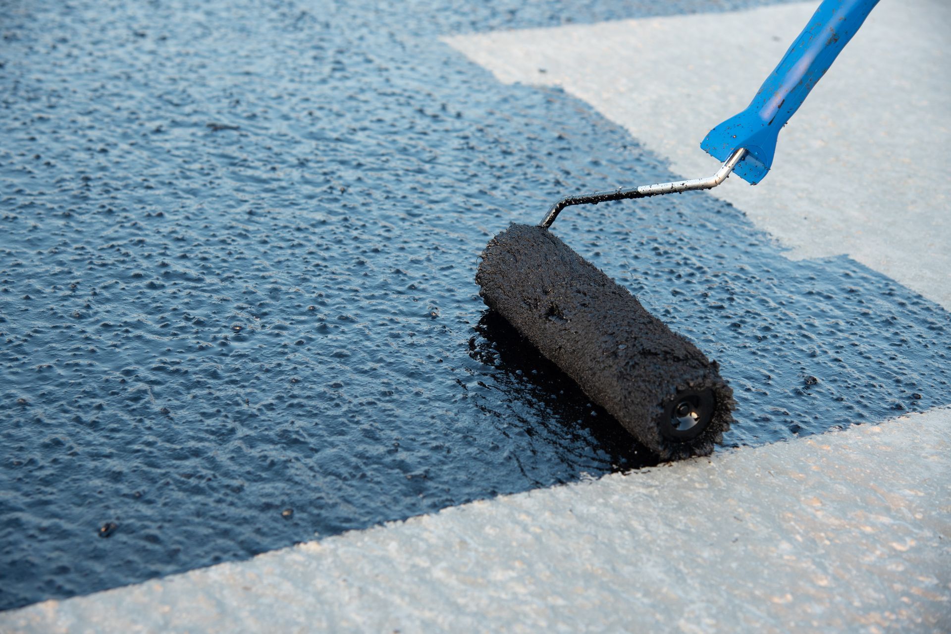 A person is painting a road with a roller.