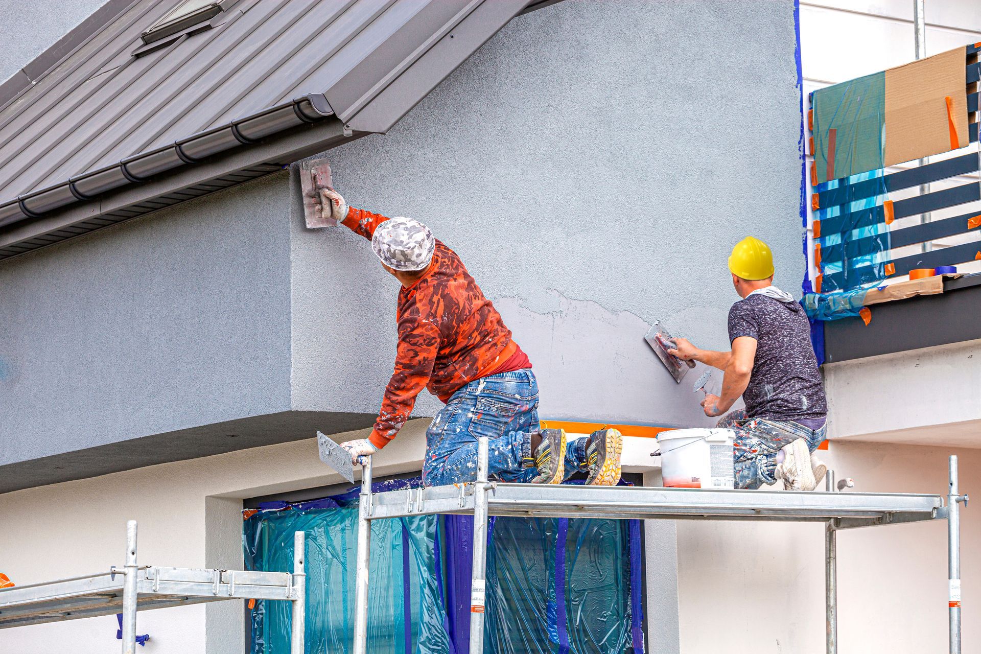 Two men are painting the side of a building.