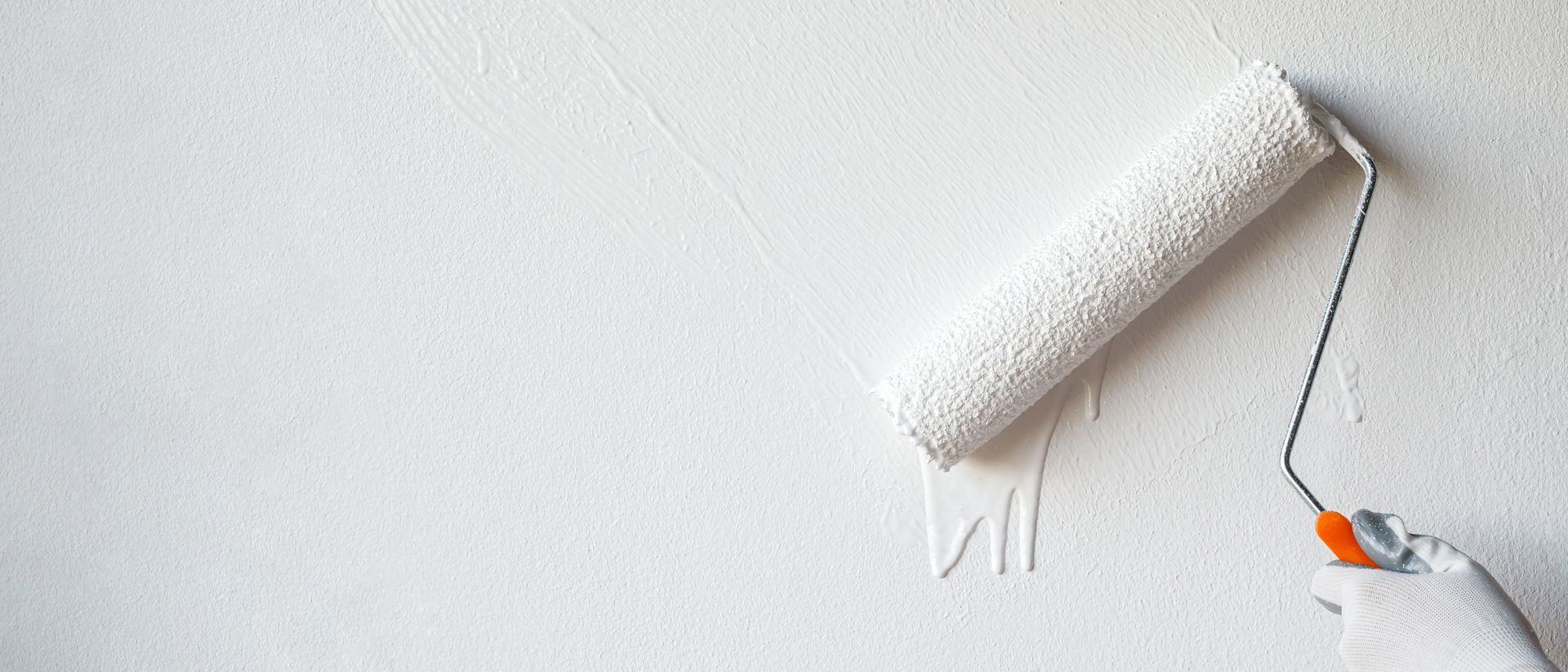 A person is painting a wall with a paint roller.