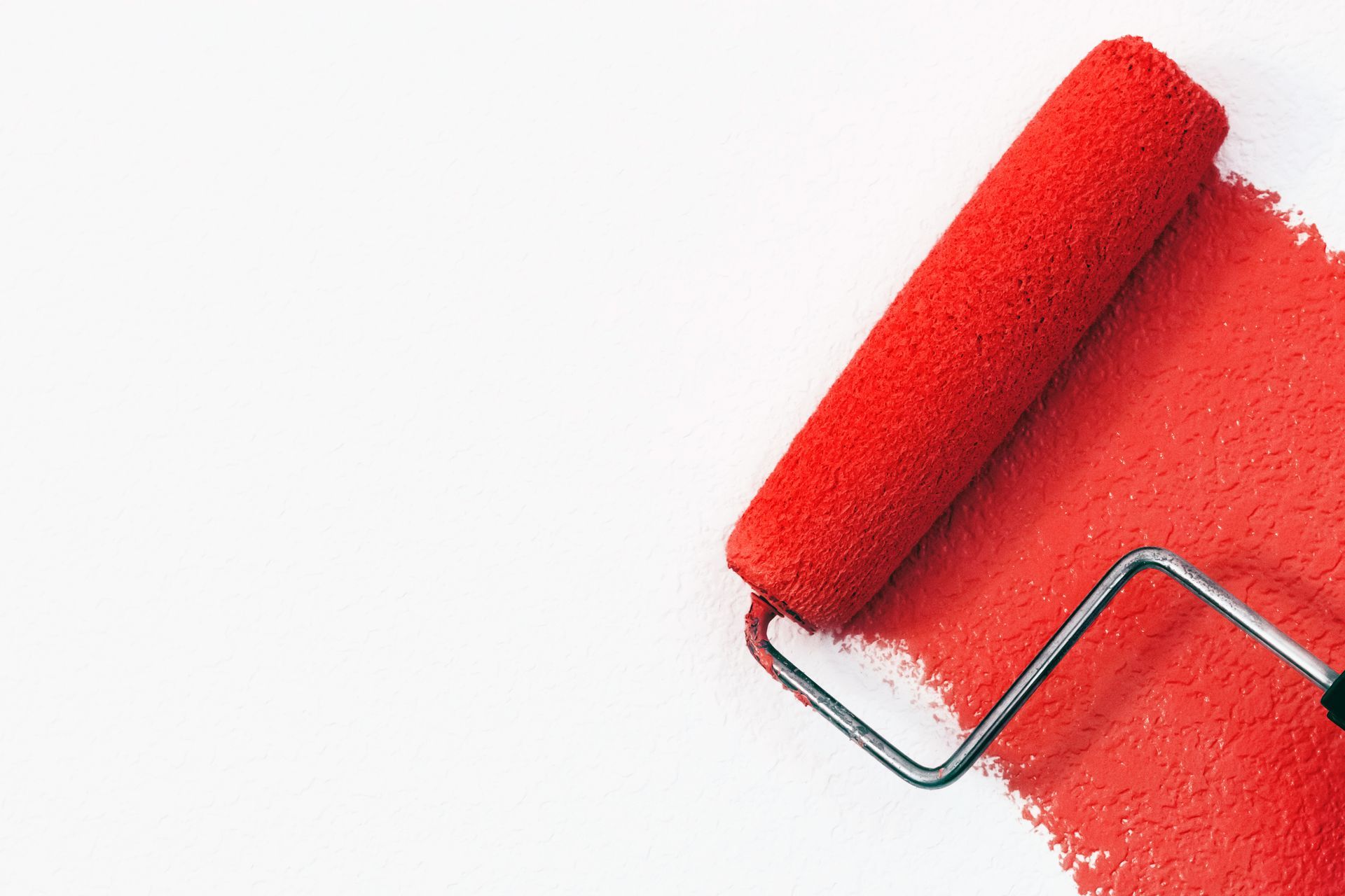 A paint roller with red paint on a white background.