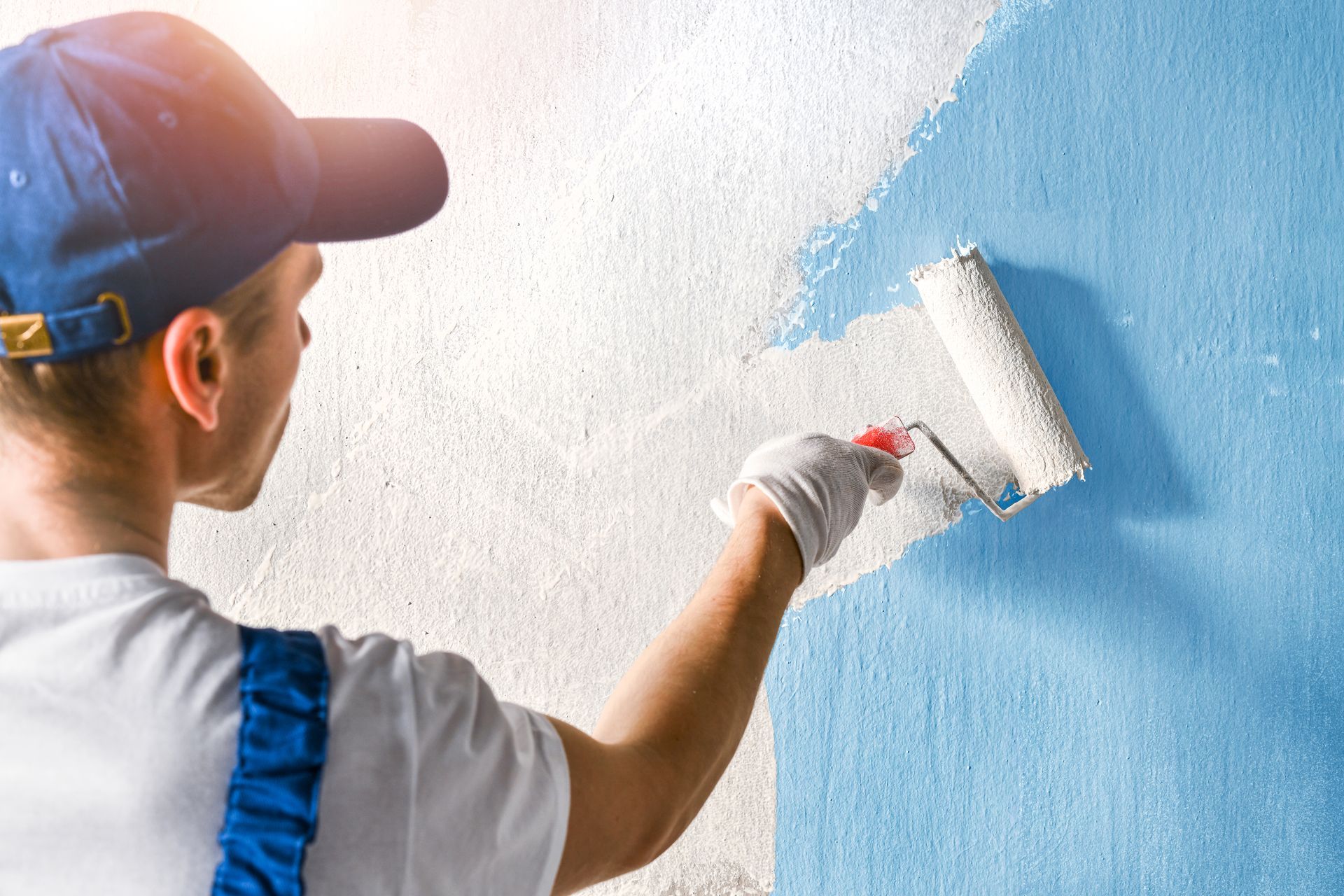 A man is painting a wall with a paint roller.