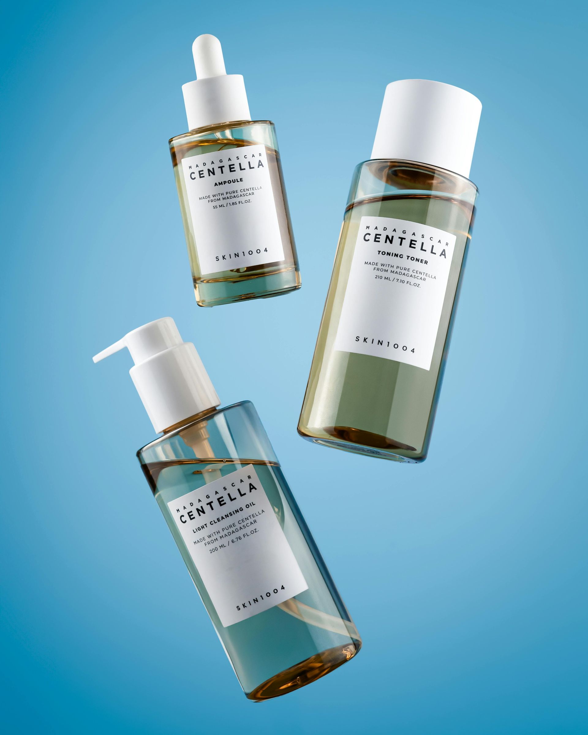 Three skincare product bottles, light blue liquid, white labels, floating on a blue background.