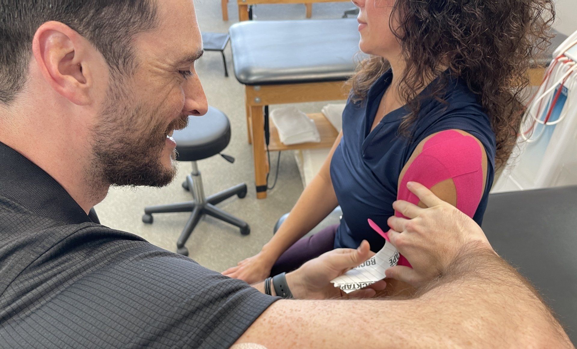 A man is applying kinesio tape to a woman 's arm.