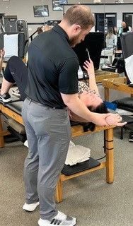 A man is helping a woman stretch her back on a table.