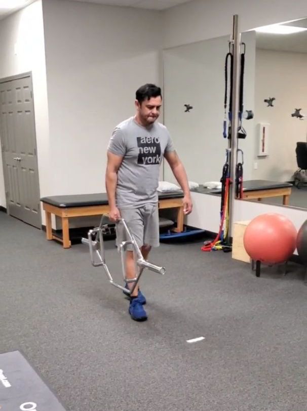 a man is carrying a hex bar to add variation into his strength training to benefit his physical therapy