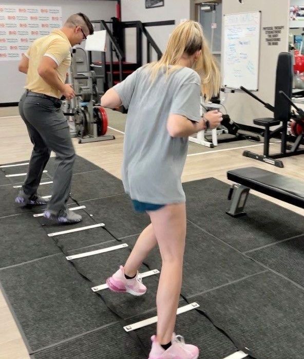 A physical therapist works with a young woman with blonde hair, she needs Physical Therapy for Sports Injuries