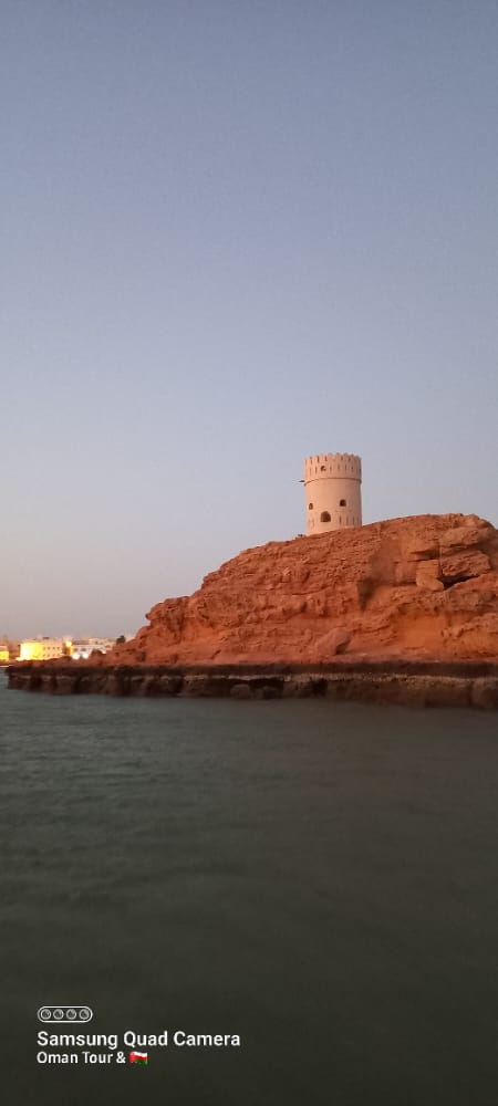 Night view of Muscat city skyline illuminated with colorful lights.