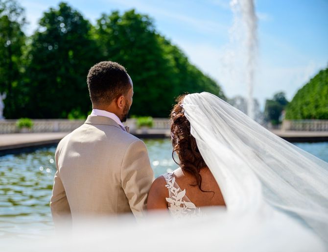 Eine Braut und ein Bräutigam sitzen vor einem Brunnen.