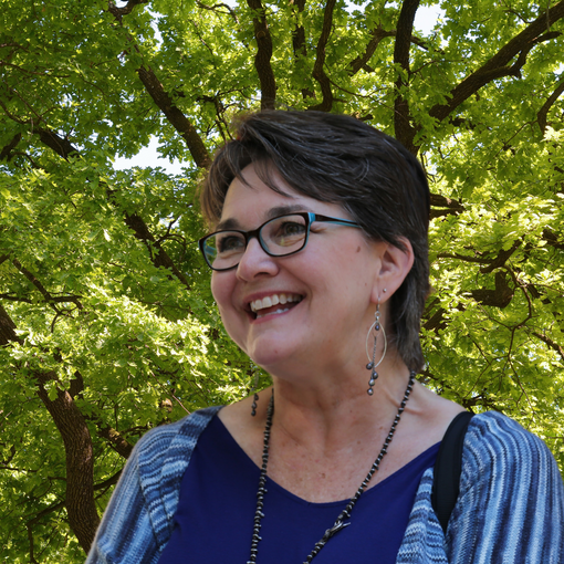 A woman wearing glasses is smiling in front of a purple background - Paula Chacon
