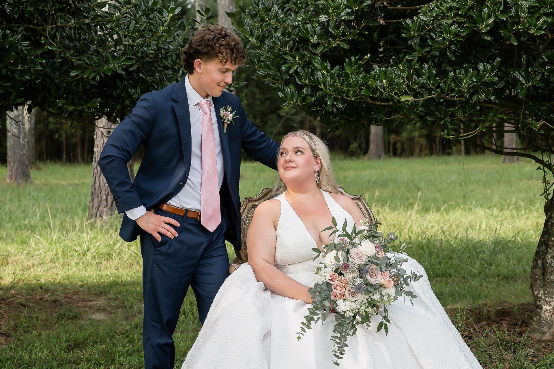 A bride and groom are posing for a picture in a field.