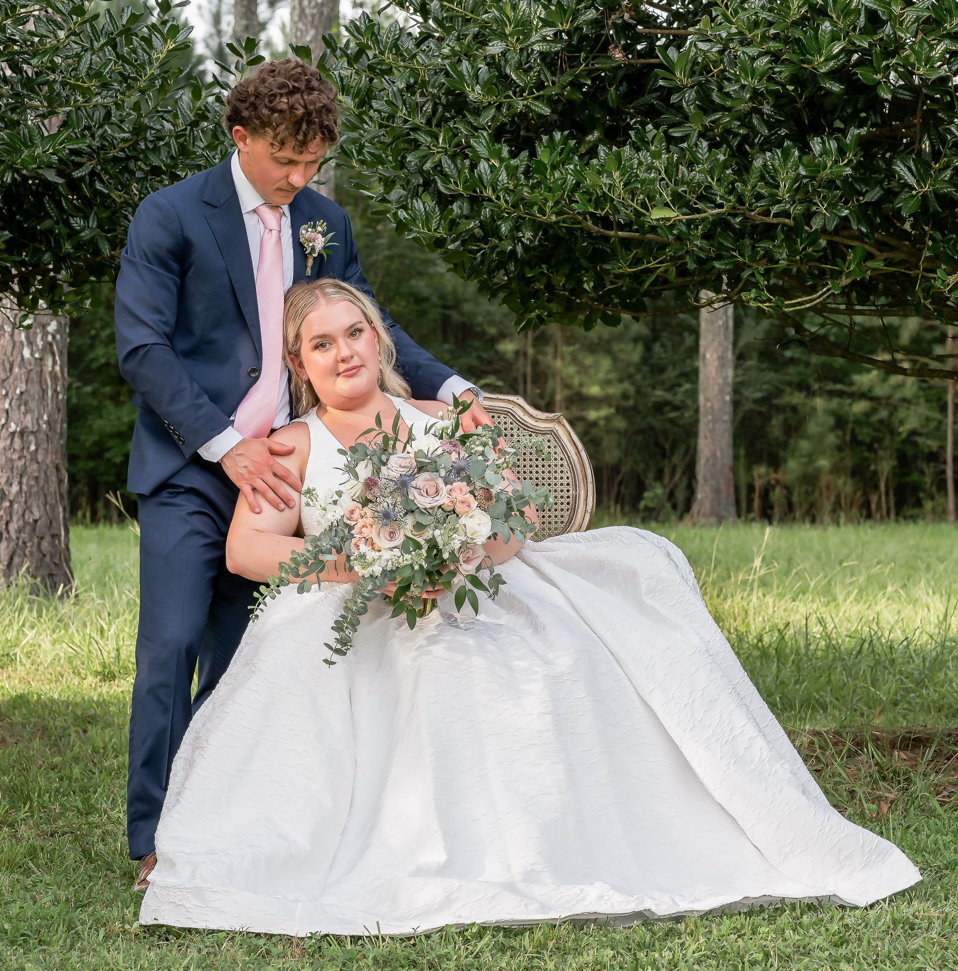 A bride and groom are posing for a picture in the grass.