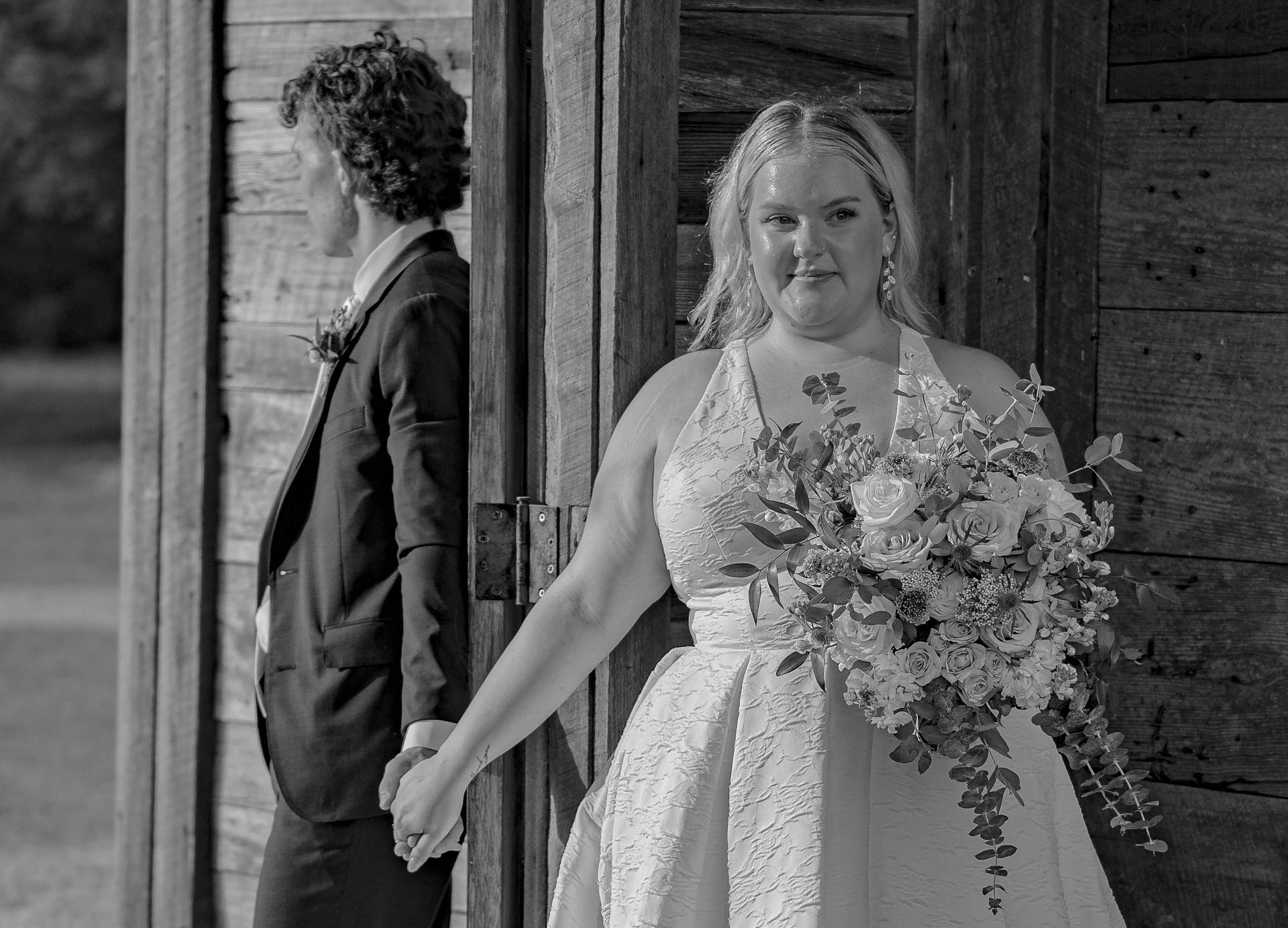 A black and white photo of a bride and groom holding hands.