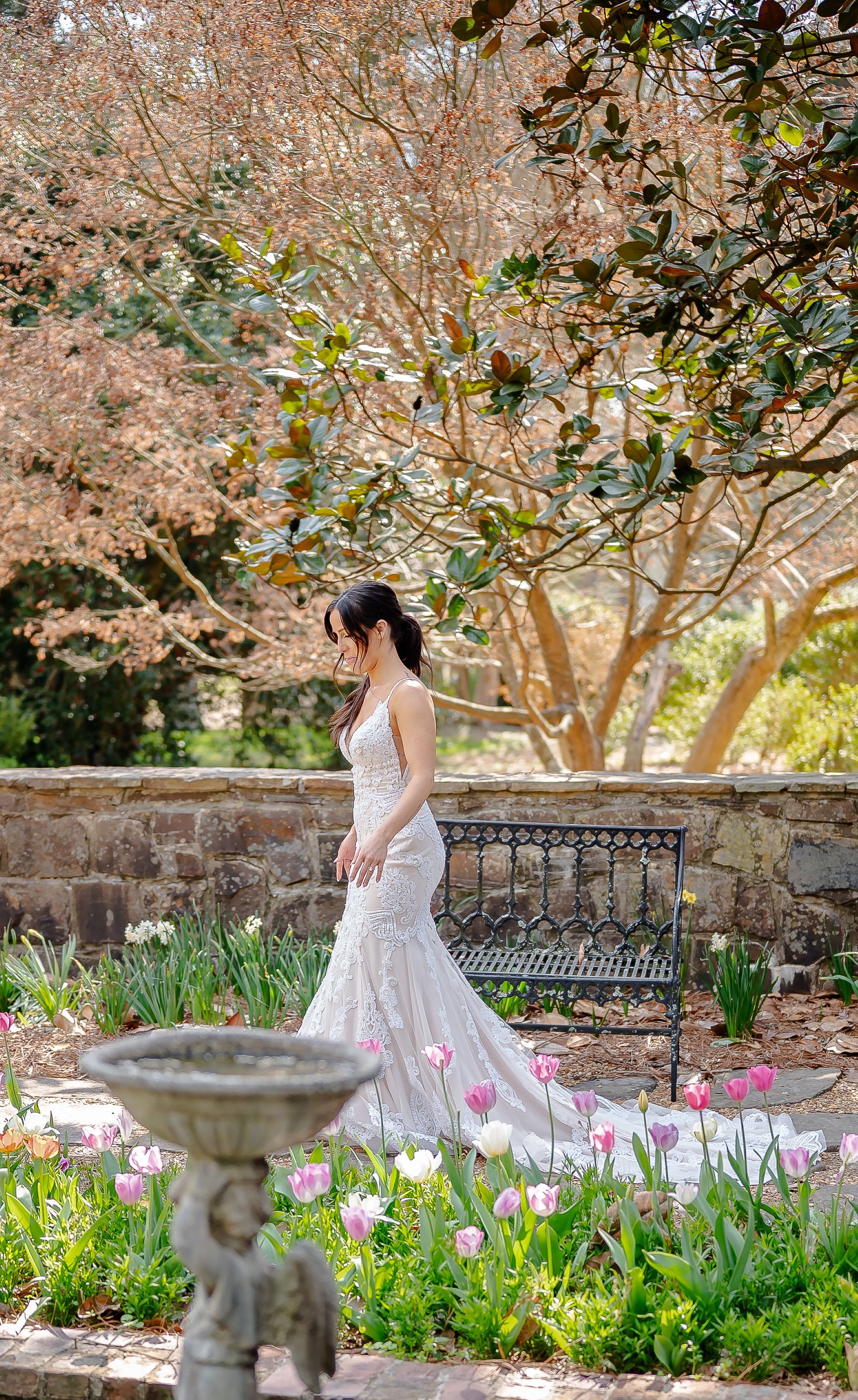 A bride in a wedding dress is walking through a garden.