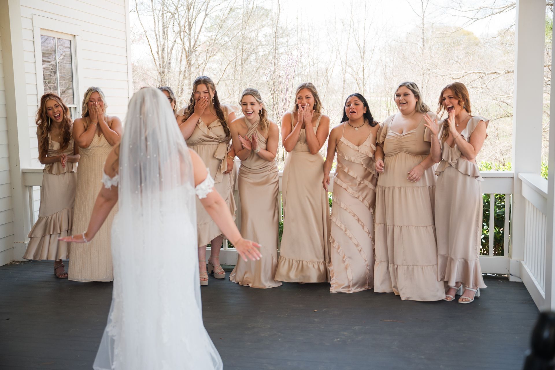 A bride and her bridesmaids first look on a porch.