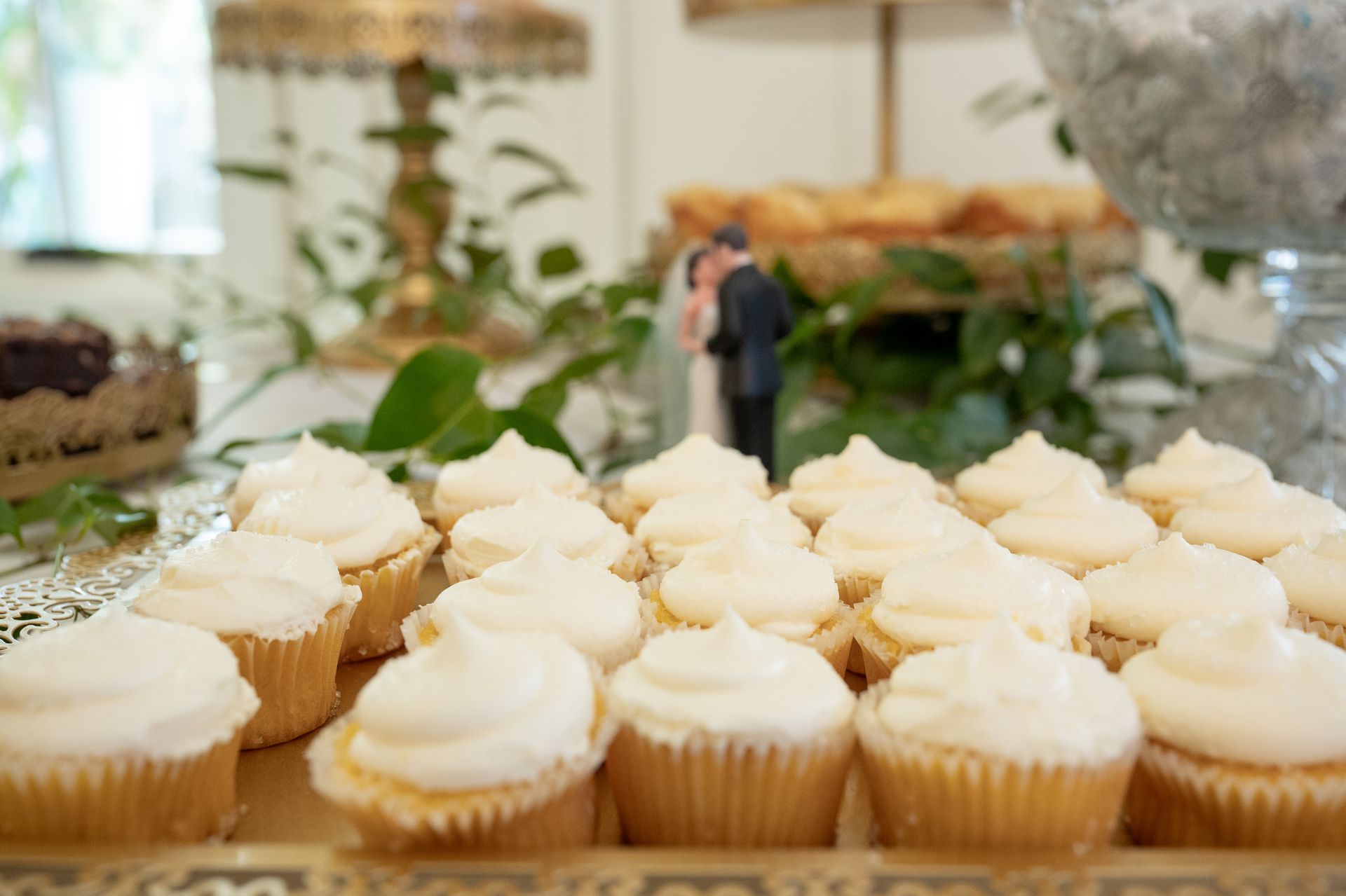 A table topped with cupcakes and a bride and groom figurine.