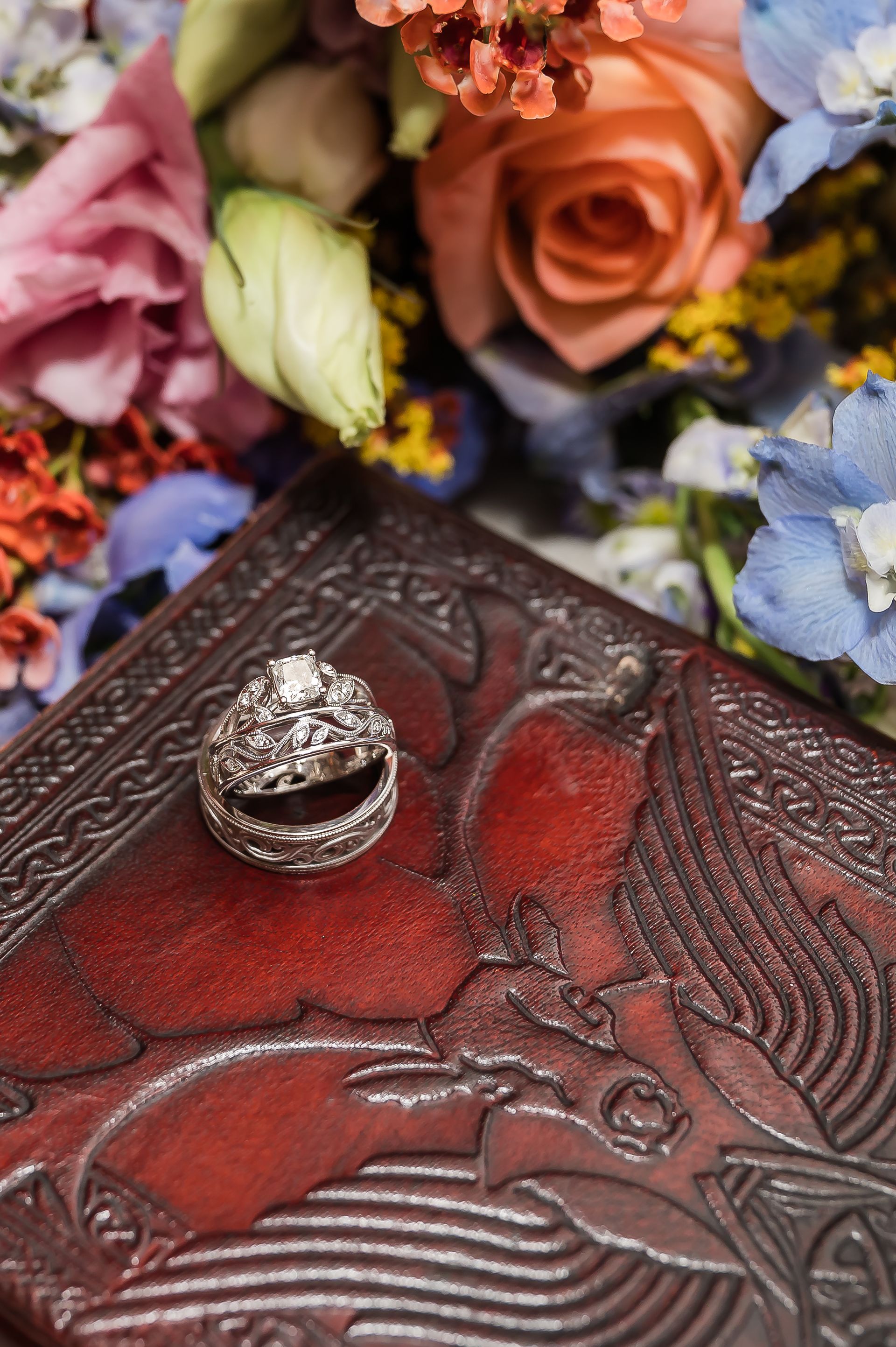A couple of wedding rings sitting on top of a book next to a bouquet of flowers.