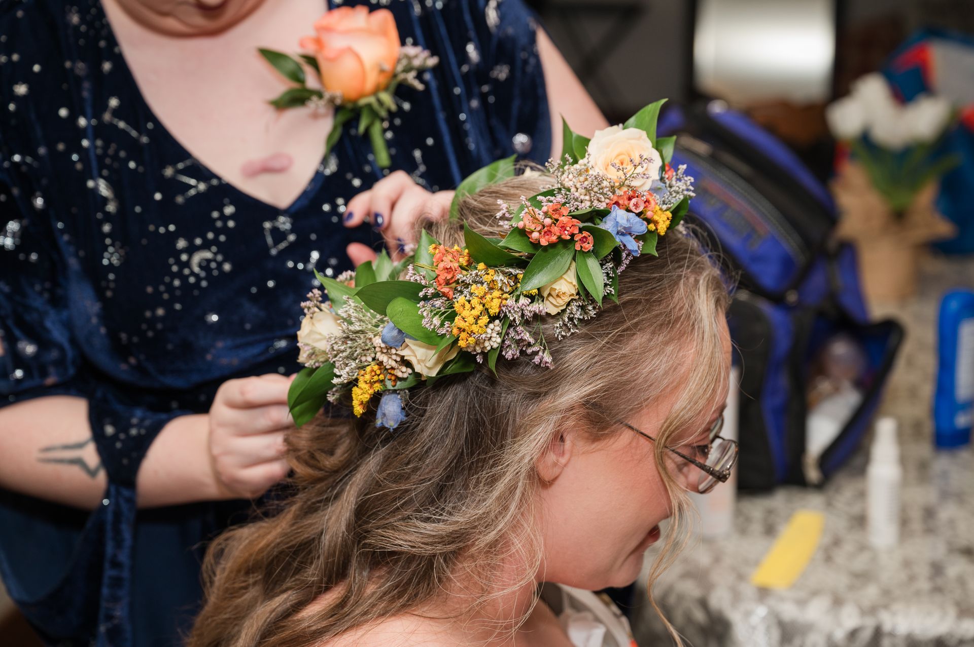 A woman is putting a flower crown on a girl 's head.