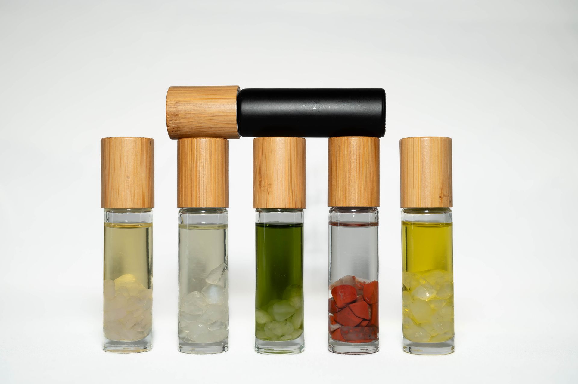 A row of essential oil roller bottles with wooden lids.