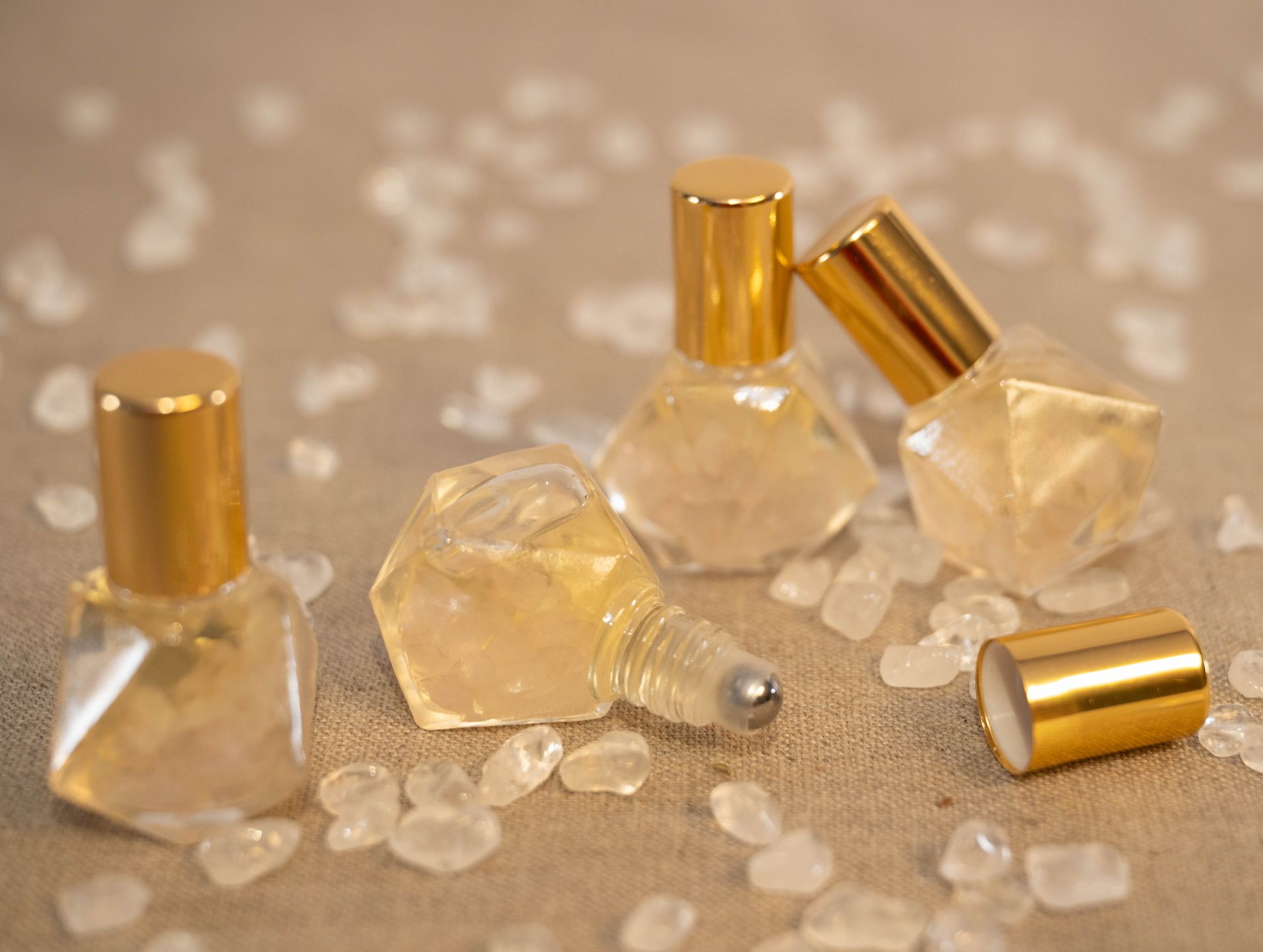 Three bottles of perfume are sitting on a table surrounded by crystals.