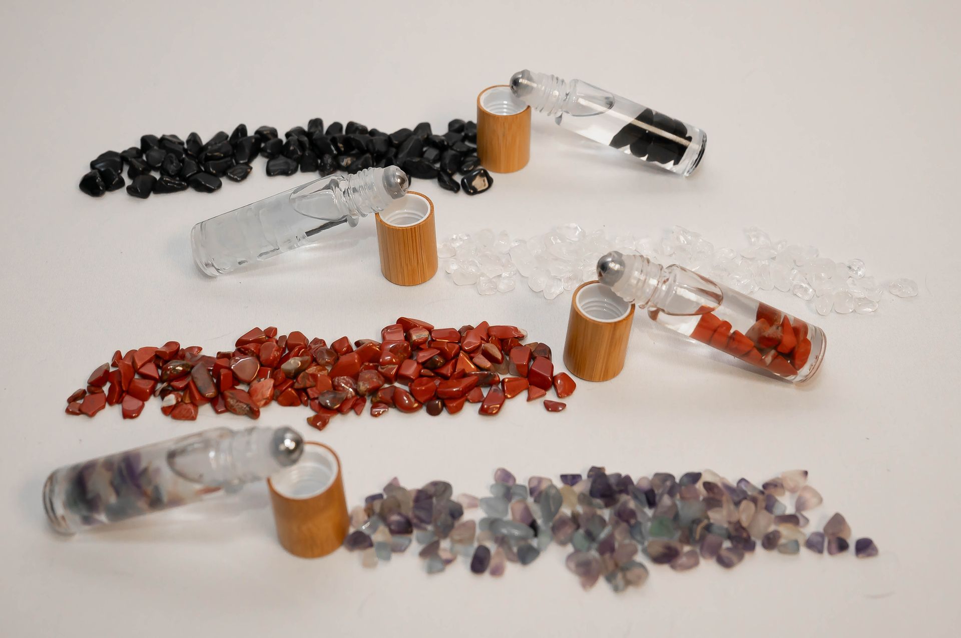 Three bottles filled with different types of crystals are sitting on a table.