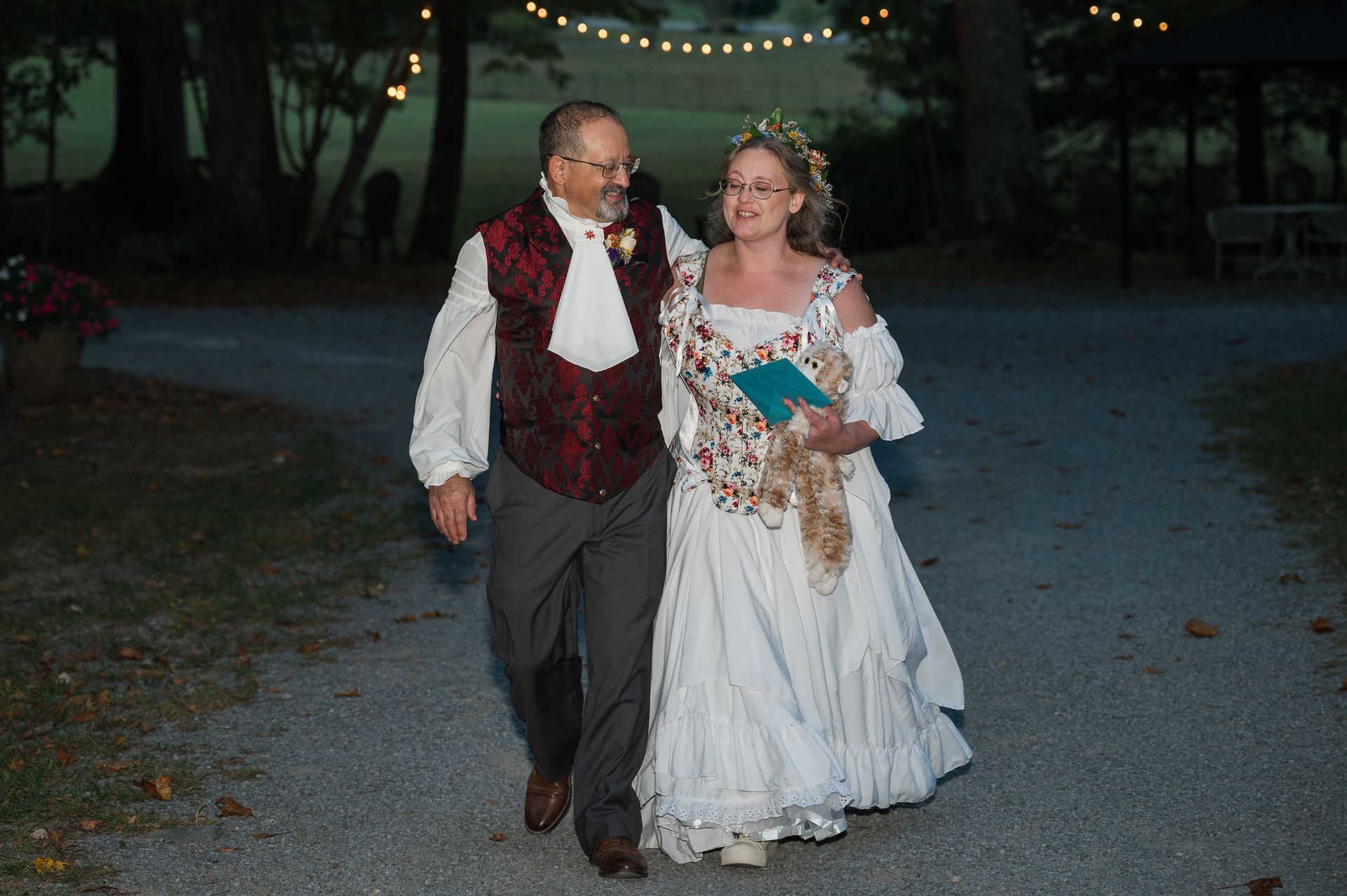 A bride and groom are walking down a path at night.
