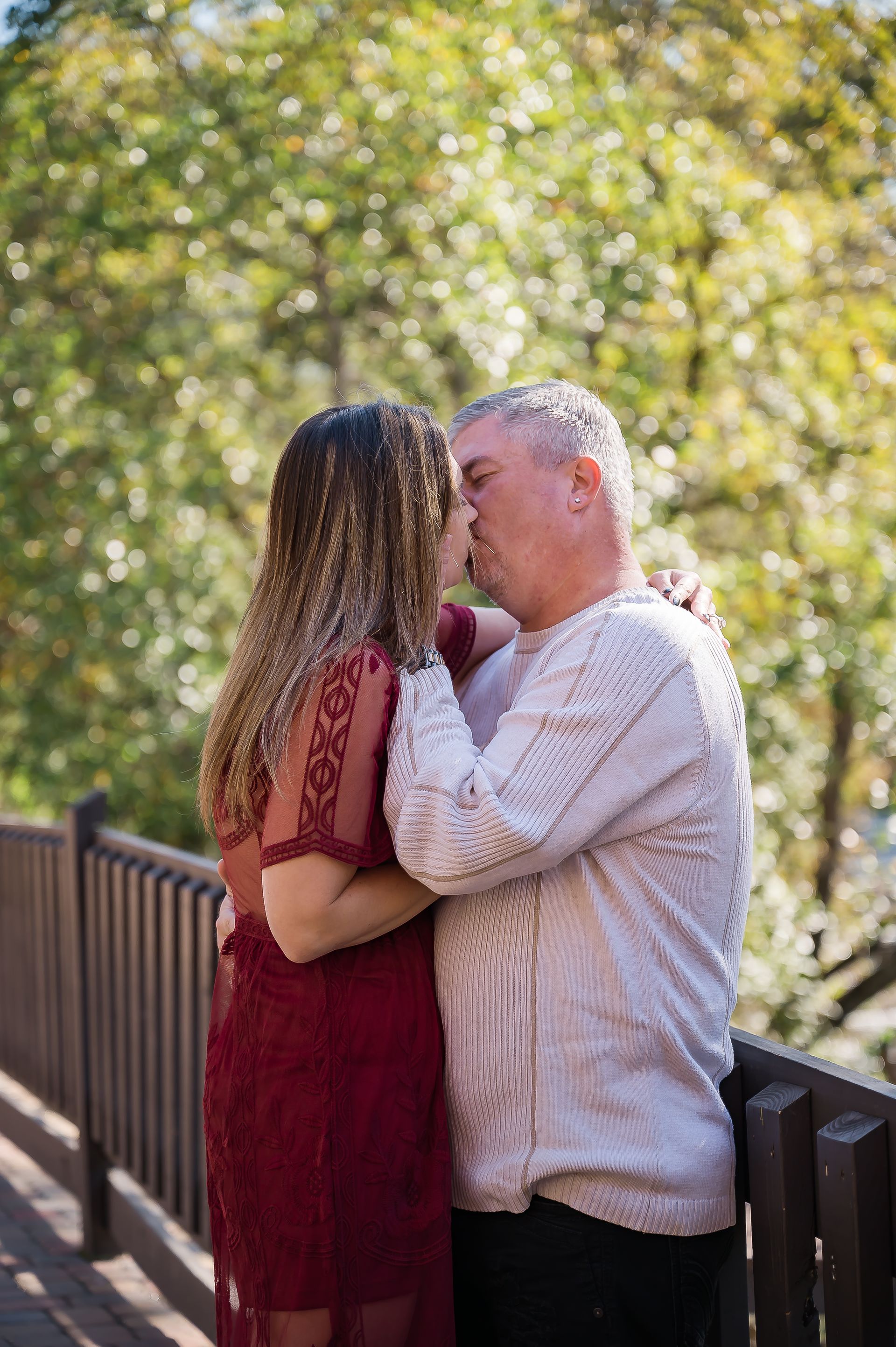 A man and a woman are kissing on a bridge.