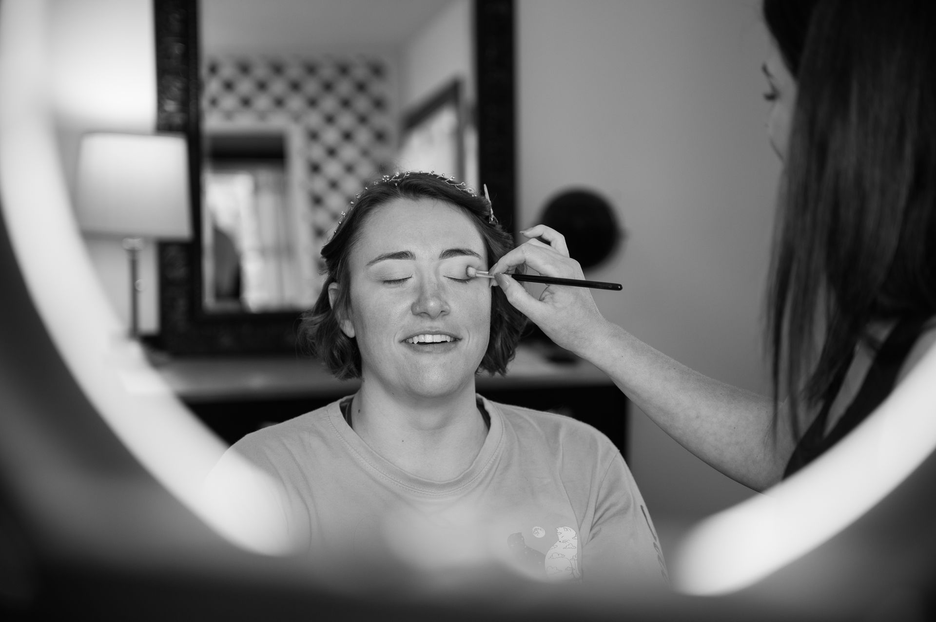 A woman is getting her makeup done in front of a mirror.