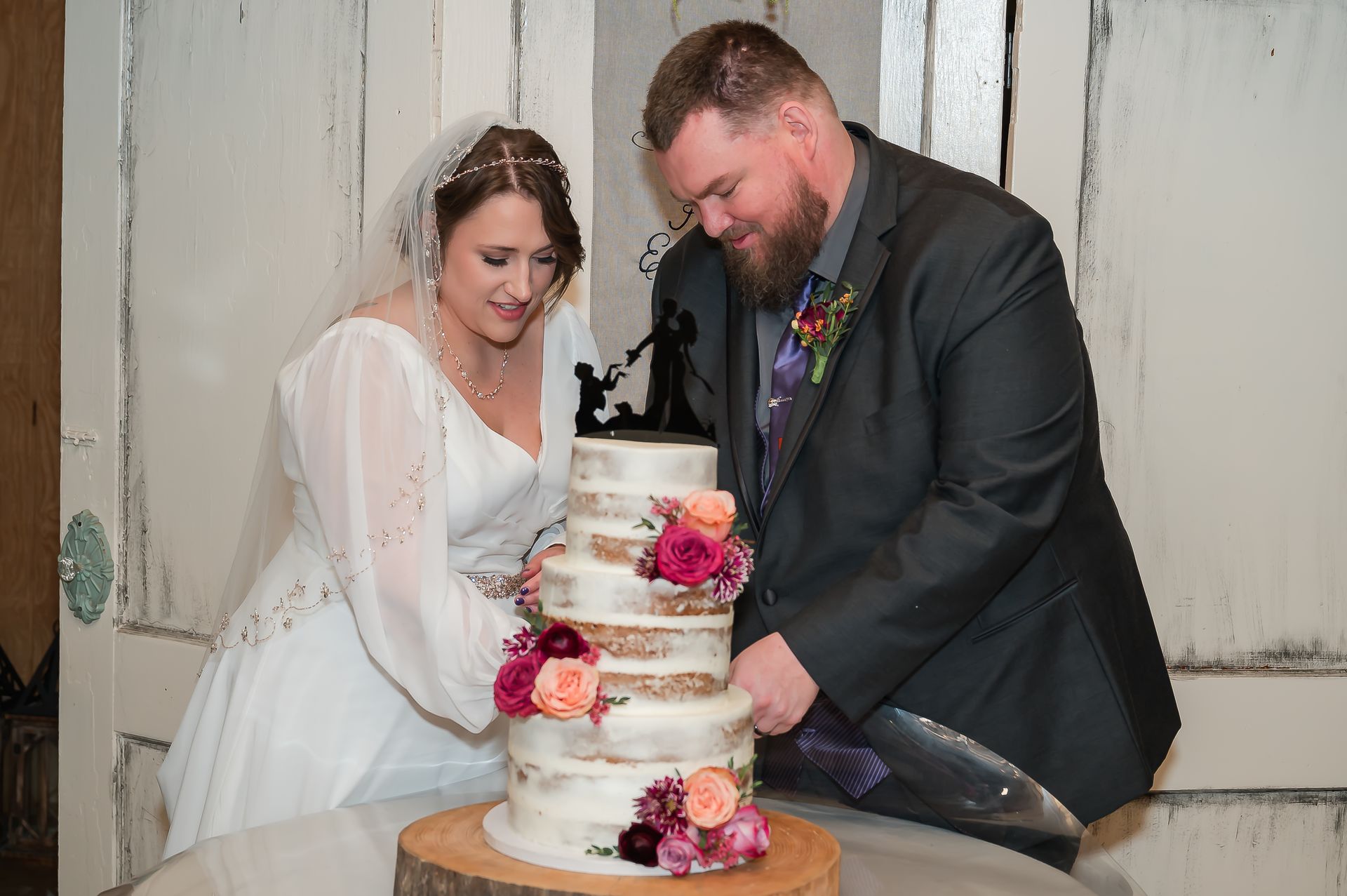 A bride and groom are cutting their wedding cake together.