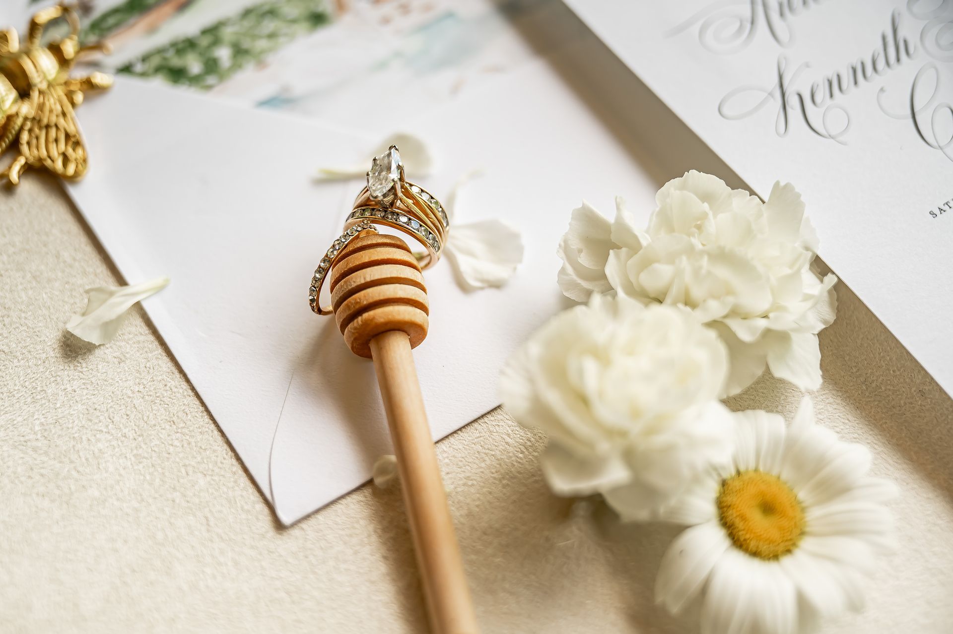 A honey dipper is sitting on top of a wedding invitation.