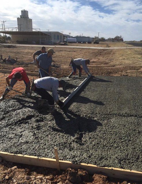 A group of construction workers are working on a concrete floor