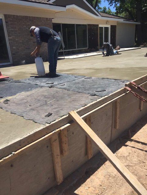A man is working on a concrete driveway in front of a house