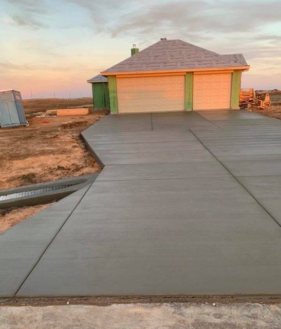 A concrete driveway leading to a house under construction.