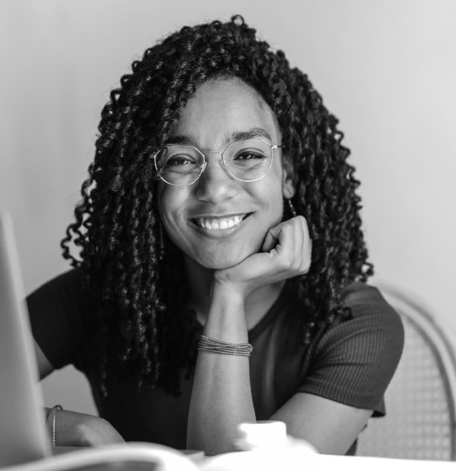 a woman with curly hair and glasses is smiling in a black and white photo