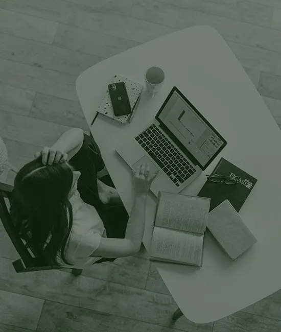 a woman sits at a desk with a laptop and a book that says phrase
