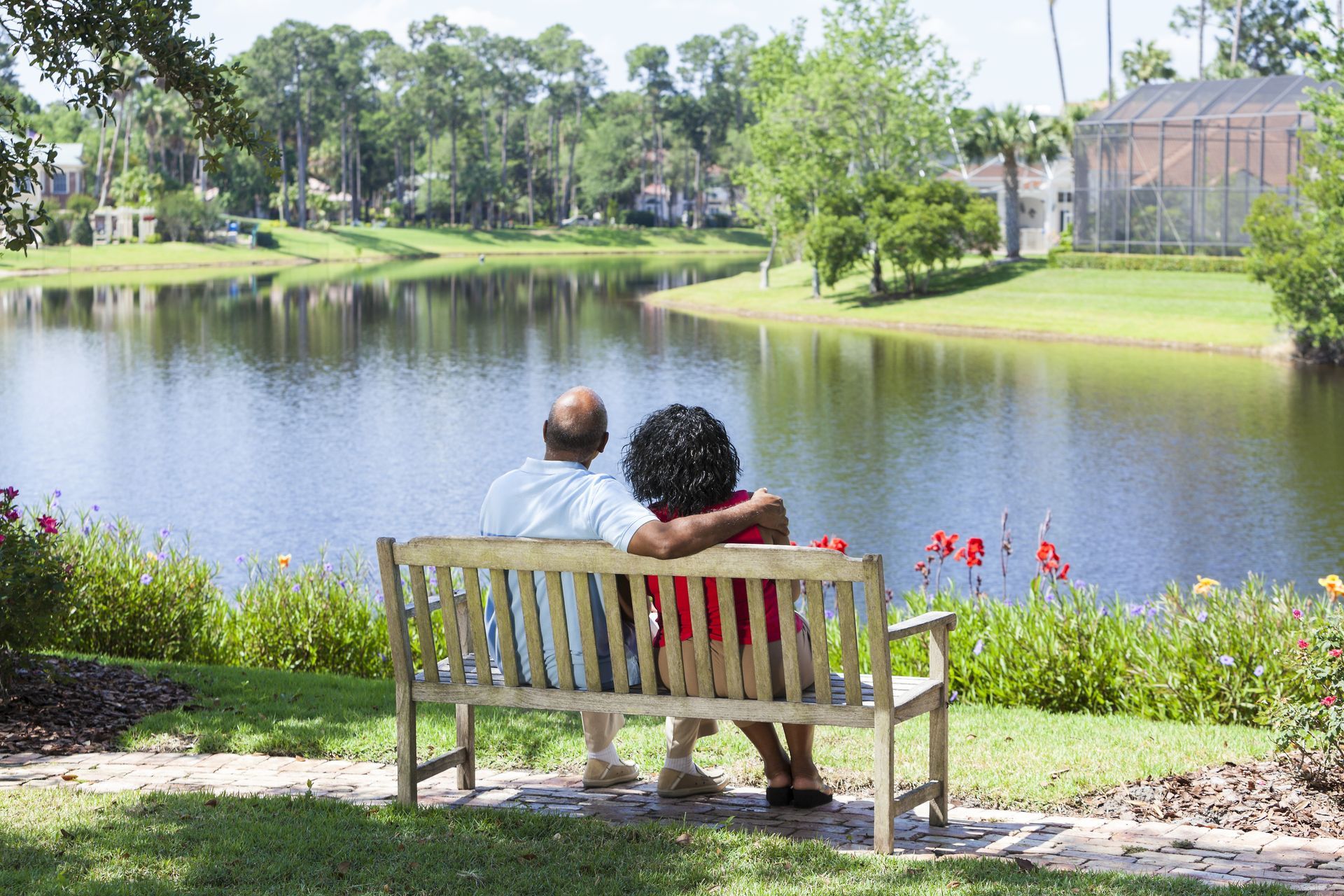 An elderly couple is sitting next to each other in front of a lake.