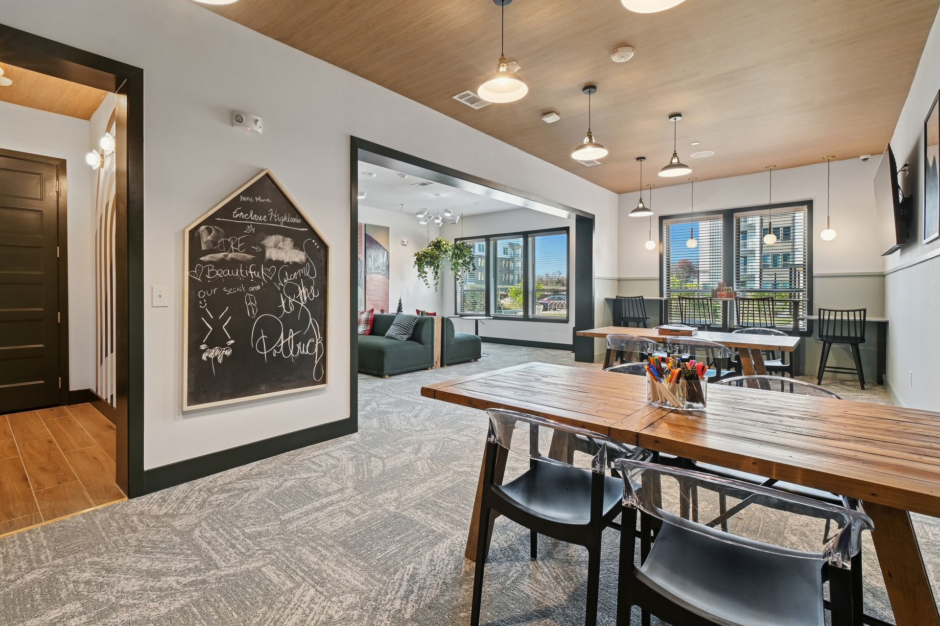 Co-working space: tables, chairs, chalkboard, window with city view, at Ennova Fulshear in Fulshear, TX.