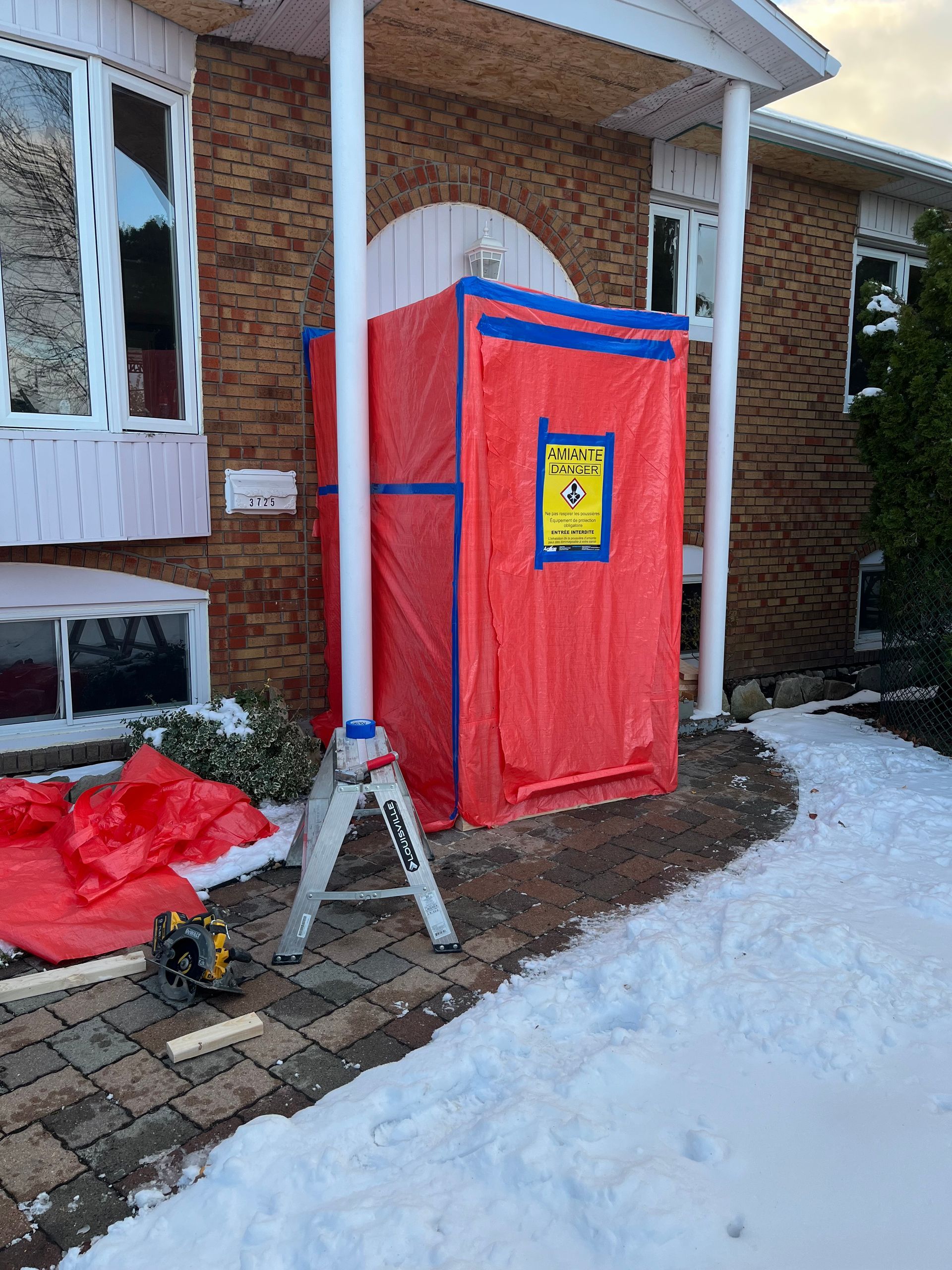 Une main gantée utilise une pince à épiler pour maintenir un petit échantillon blanc et fibreux à côté de roches grises.