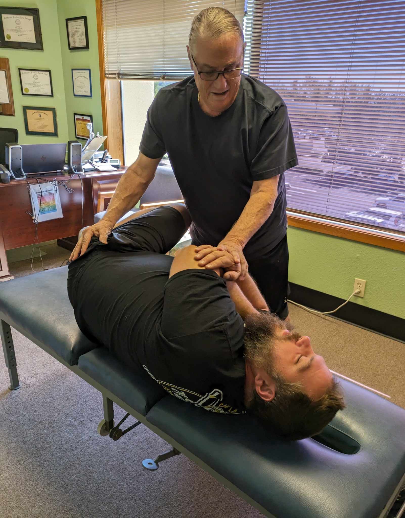 A man is laying on a table getting a massage from a doctor.