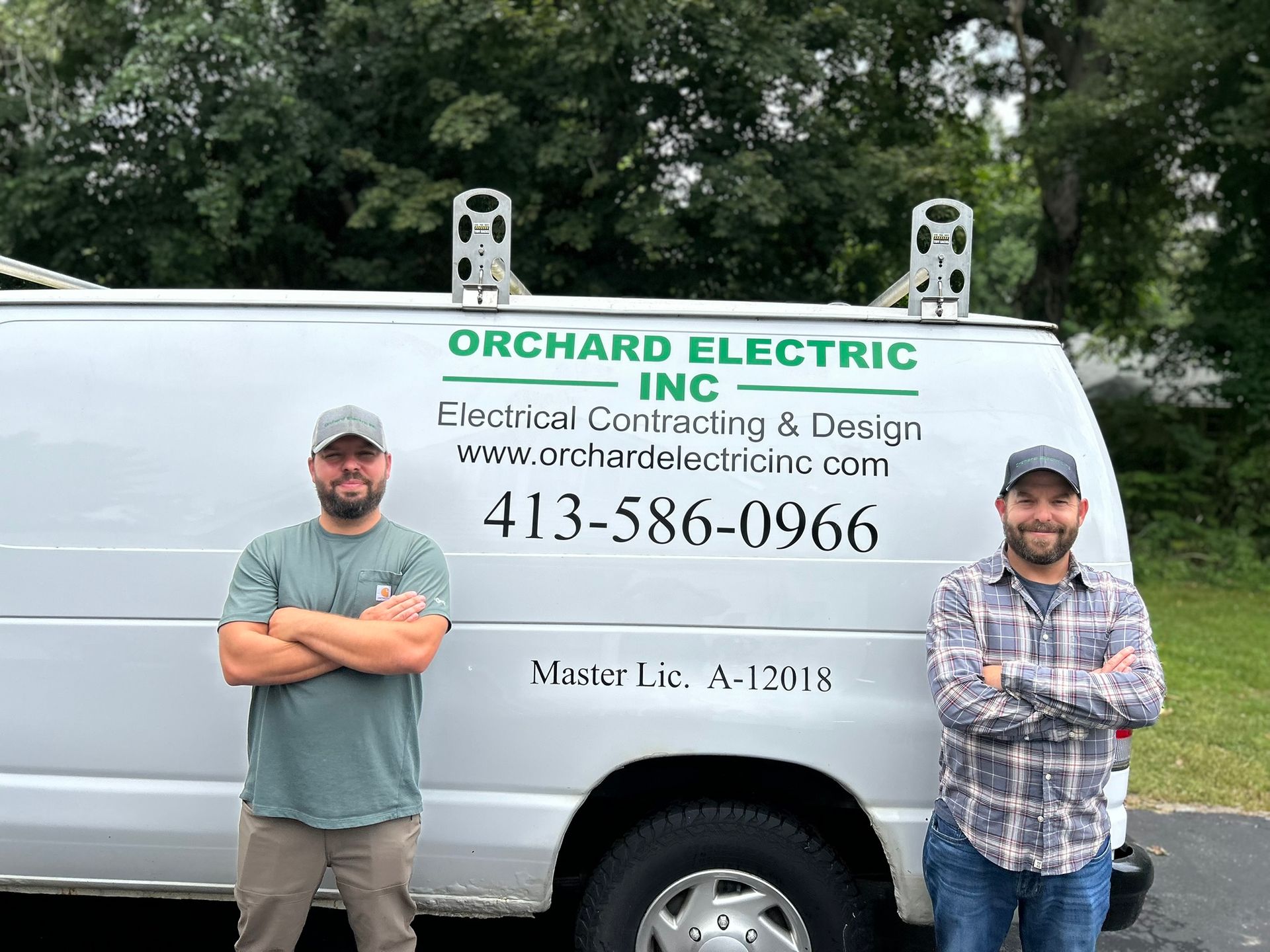 Two men posing by a white Orchard Electric van.