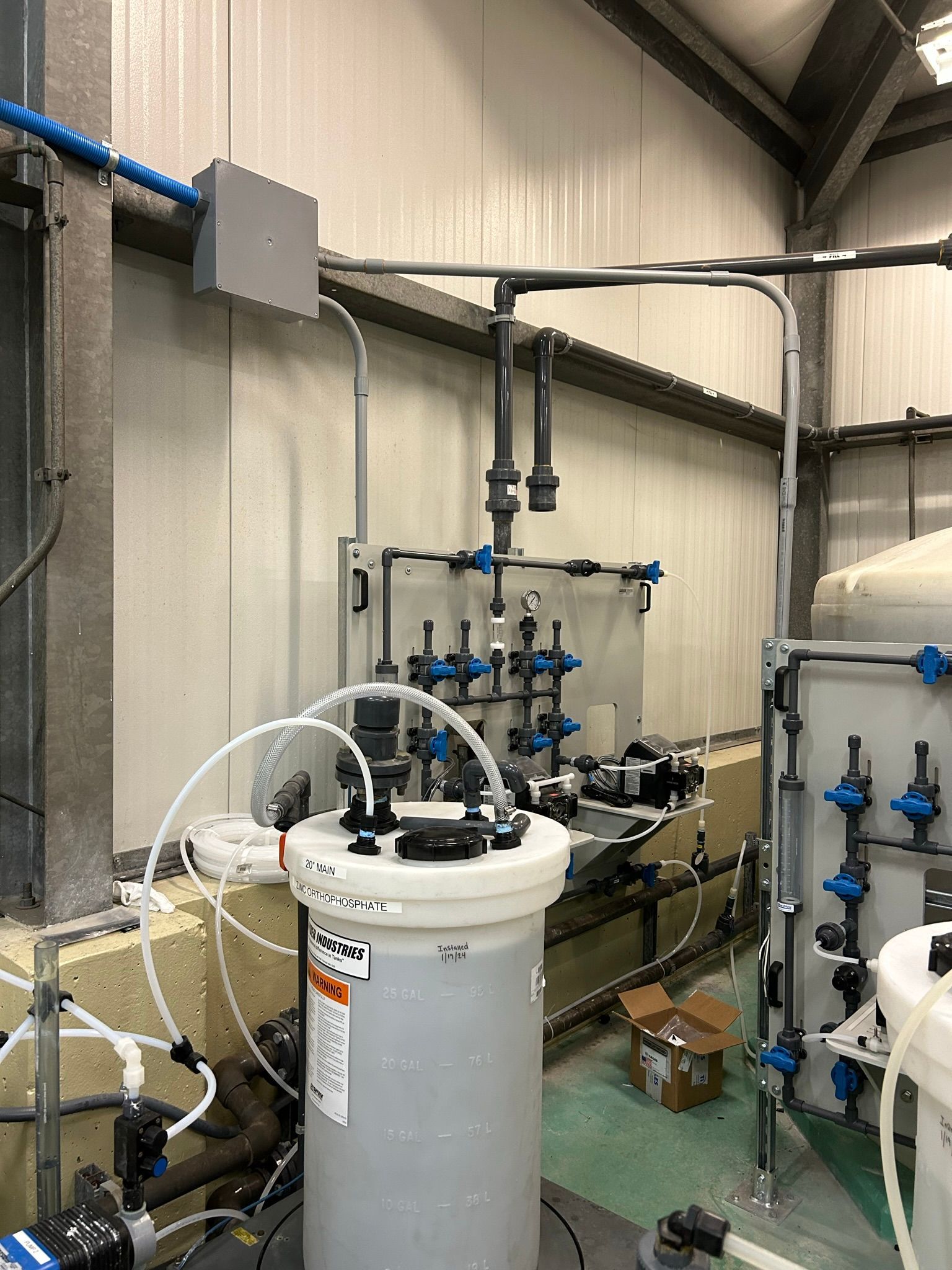 Chemical mixing system inside a building with tanks, pipes, and valves.