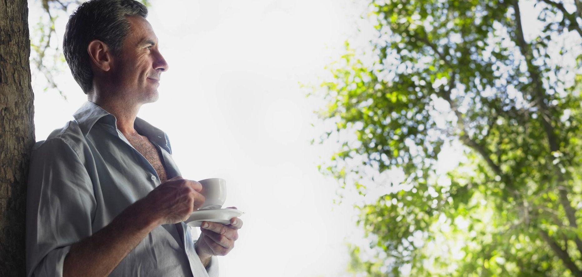 A man enjoys a cup of coffee looking out at nature.