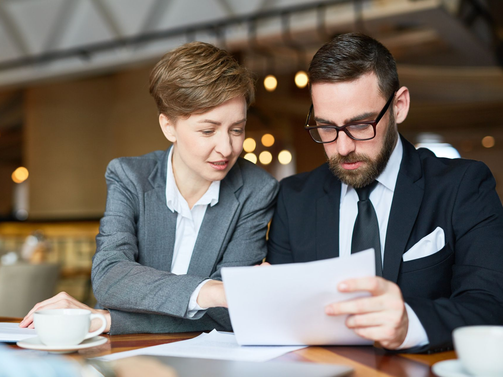 Two people in business attire reviewing documents at a table.