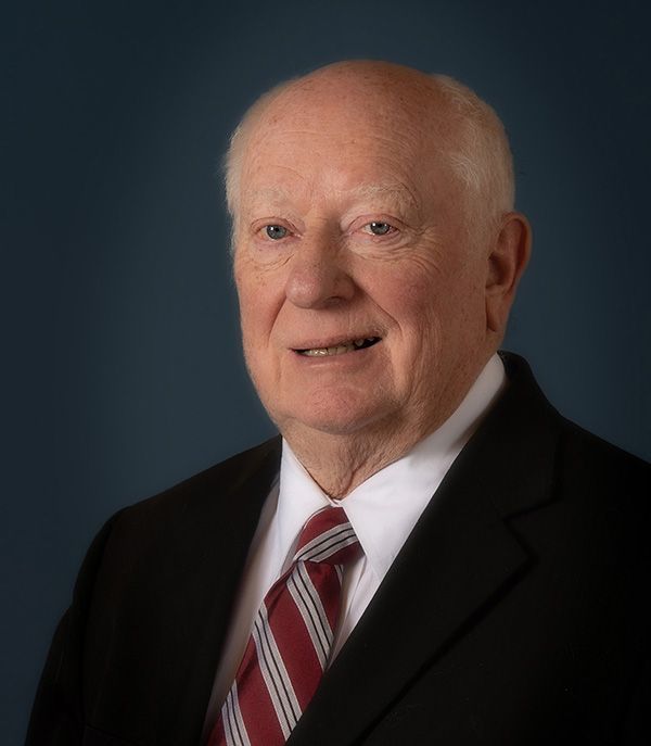 A man in a suit and tie is smiling for the camera