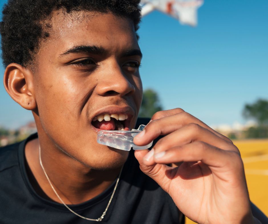Teen athlete inserting a sports mouthguard.
