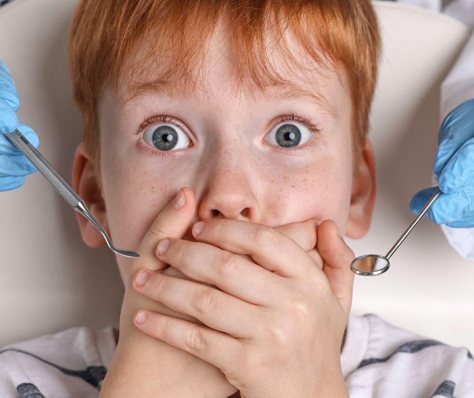 Frightened child covering mouth during a dental visit.