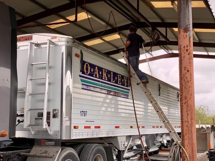 man power washing the top of the trailer truck