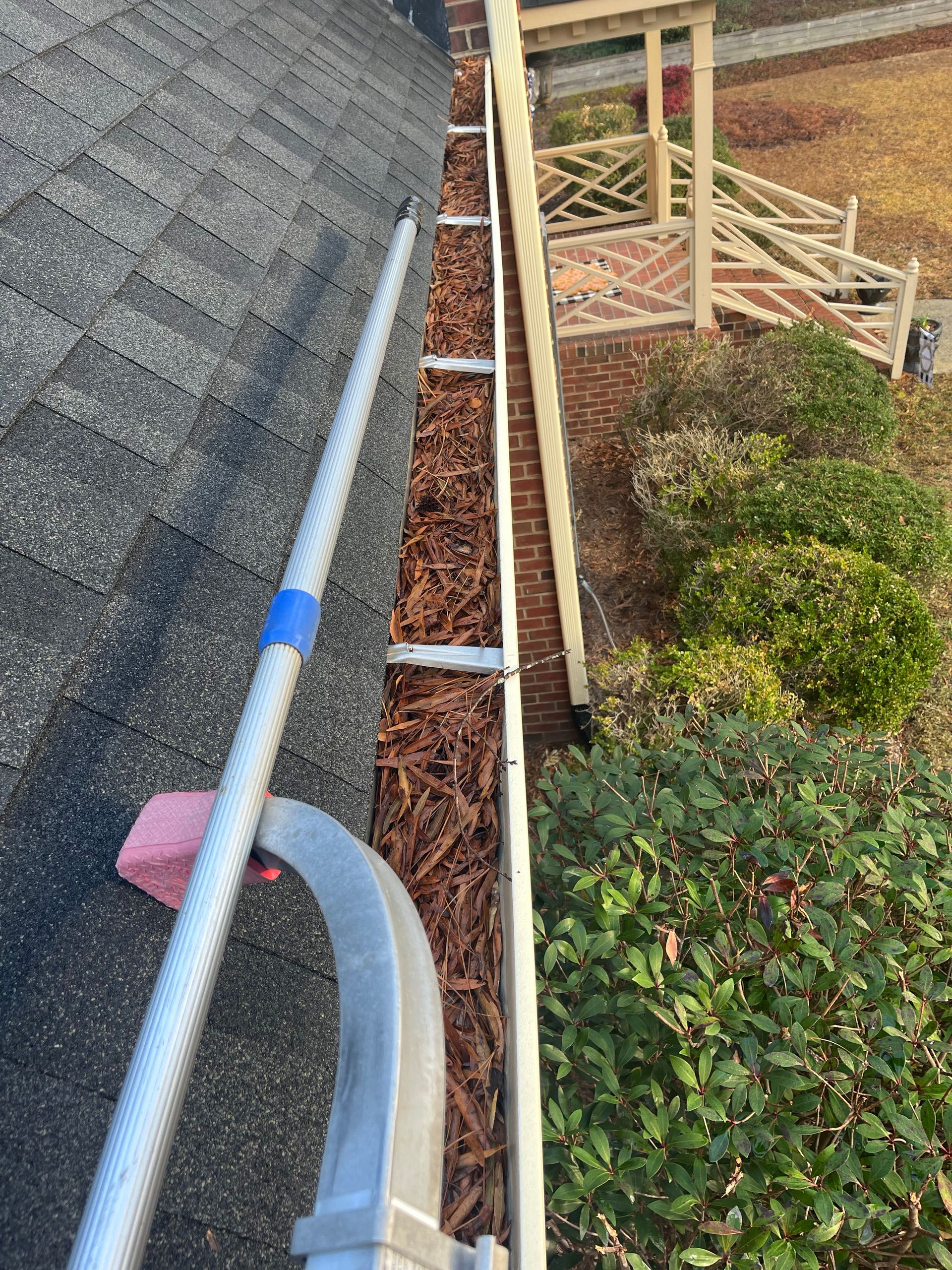 A gutter is being cleaned on the side of a house.