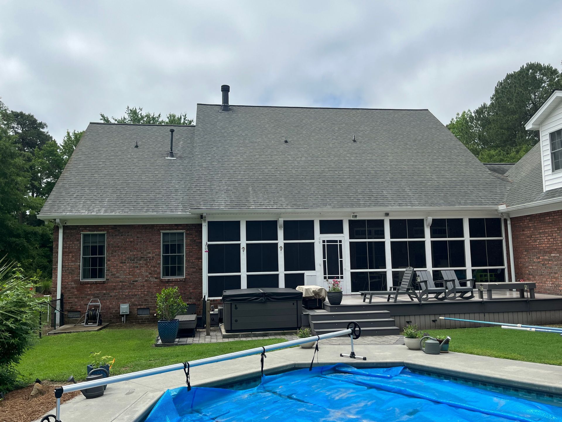 The back of a brick house with a screened in porch.